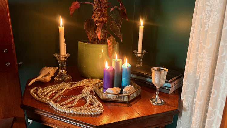 Purple, silver and blue shimmer wax play candles lit among pearls and shells, The Bower by Collared Foxy