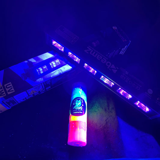 Beamz BUV63 UV light panel lit, with a UV reactive wax play candle glowing beneath it